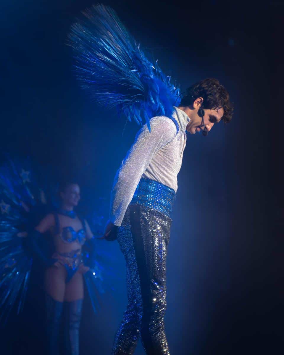 Spectacle de cabaret avec performer en costume scintillant et plumes bleues à Marseille.